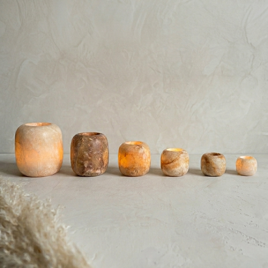 Brown Alabaster candle holders with varying sizes on a textured surface.