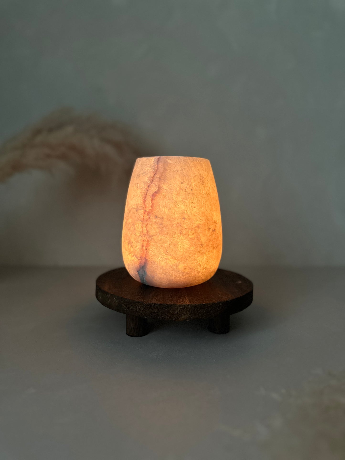 Decorative Alabaster lamp with a warm glow on a wooden base against a plain background