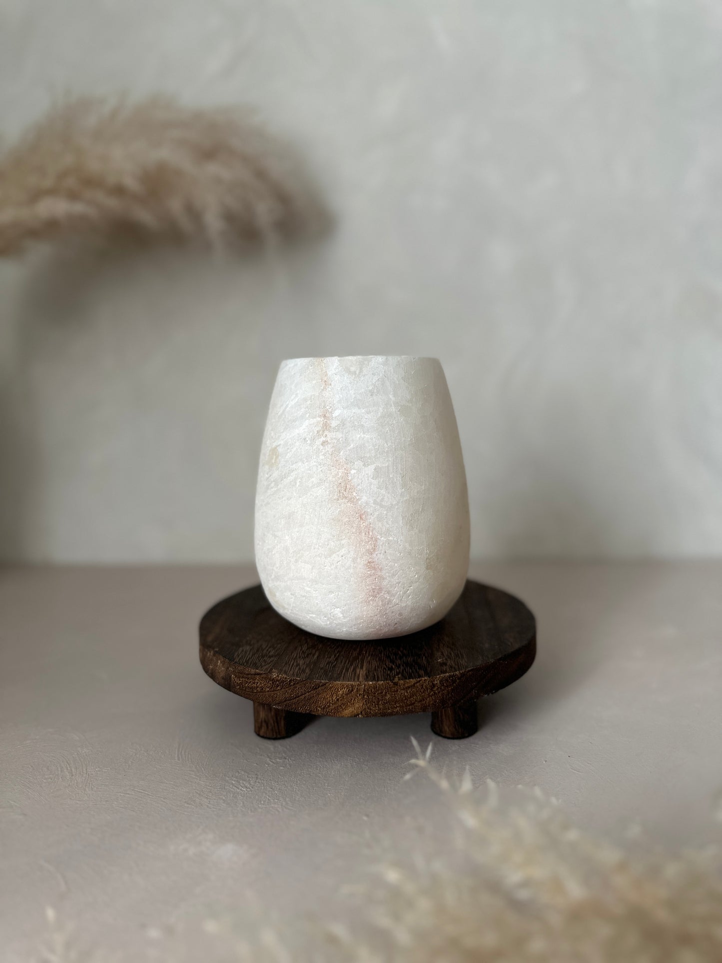 White textured Alabaster vase on a wooden stand against a neutral background