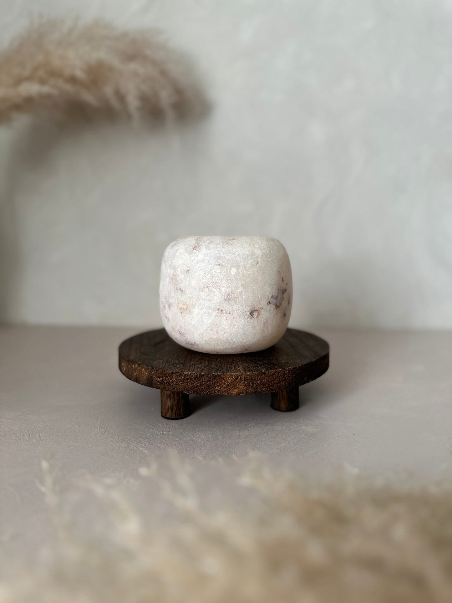 White Alabaster pot on a wooden stand with a blurred background
