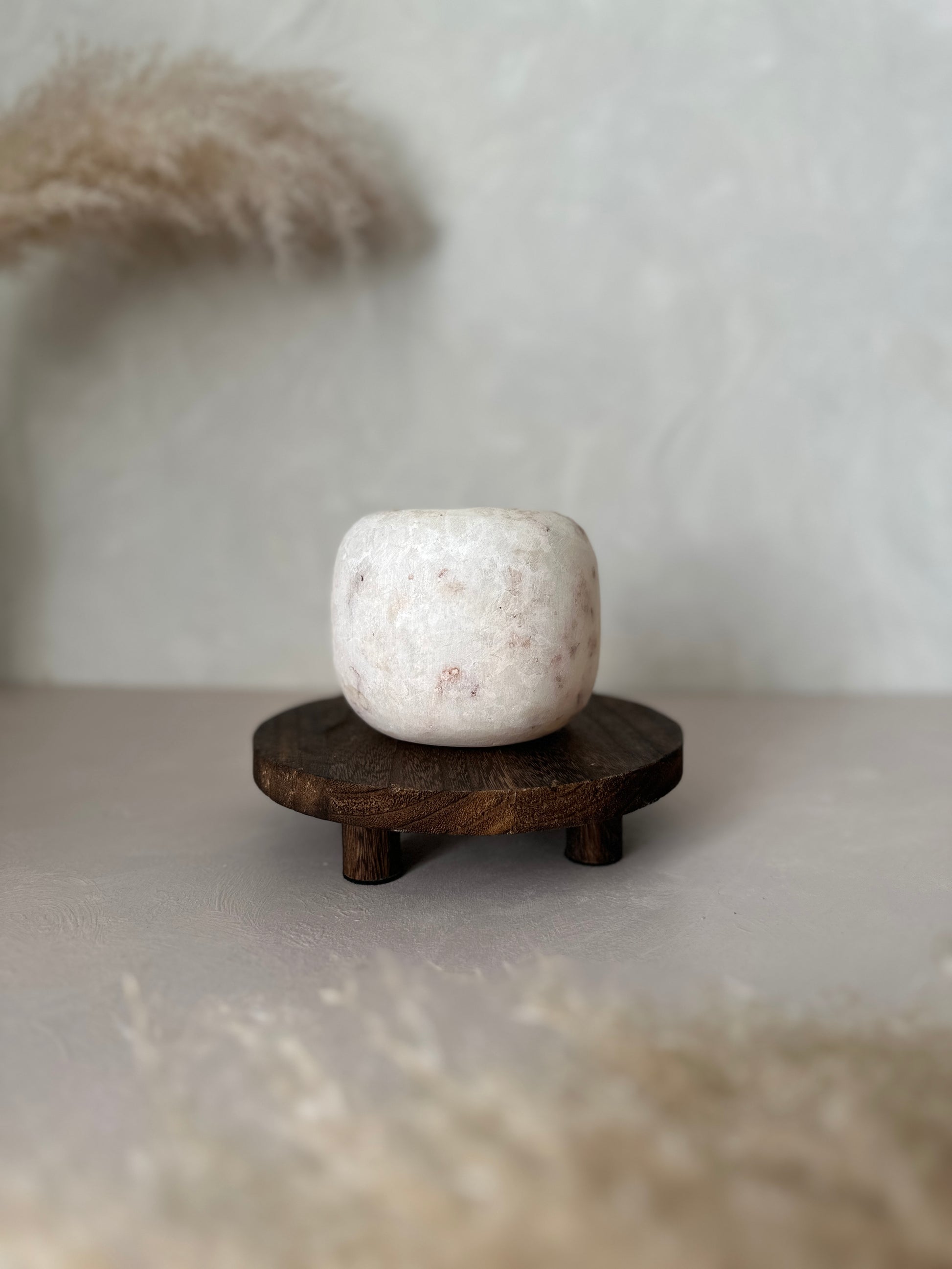 White Alabaster bowl on a wooden stand with a neutral background
