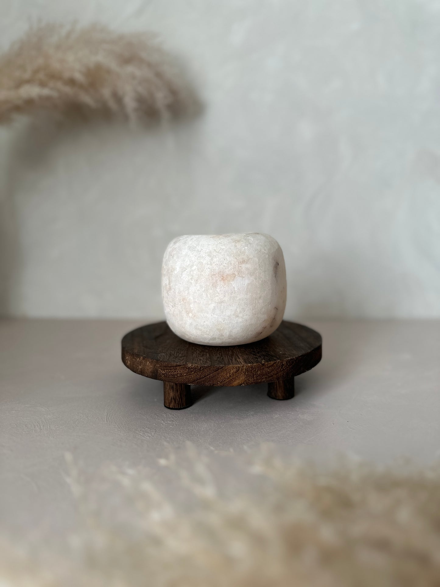 White Alabaster vase on a wooden stand with a blurred background